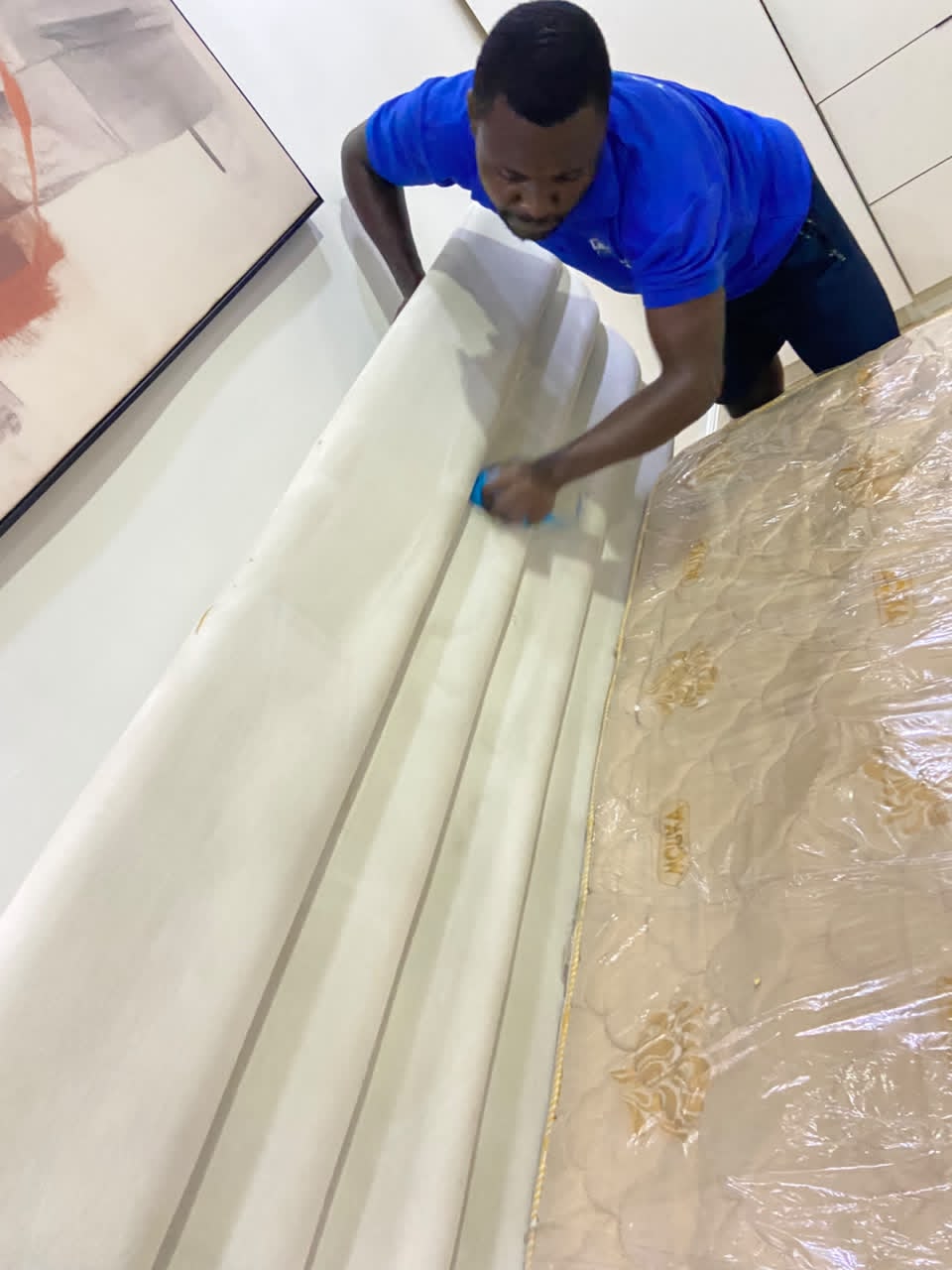 cleaner deep cleaning an upholstered bed frame in a Lagos home