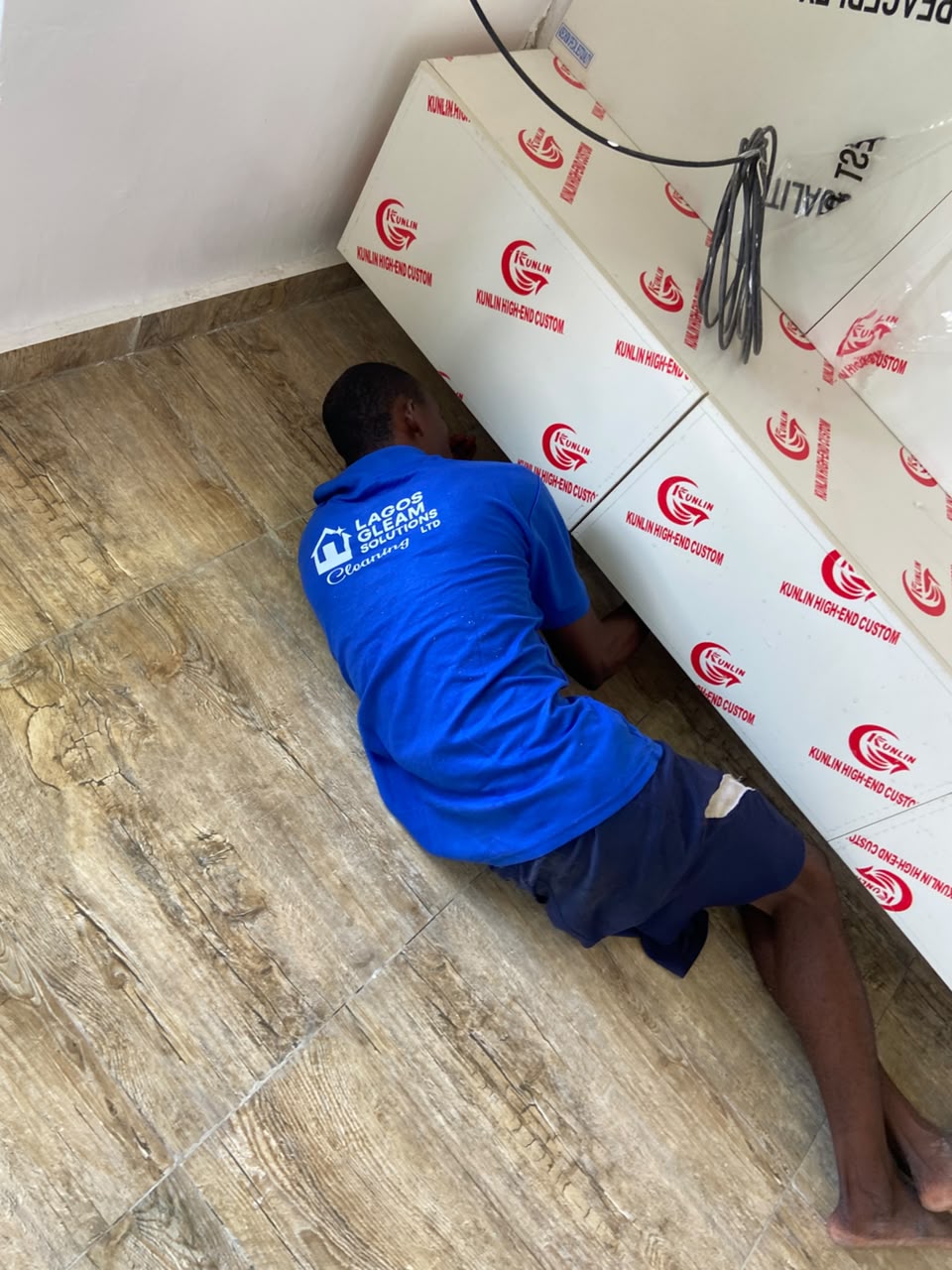 cleaner detailing under a kitchen cabinet during post-construction cleaning