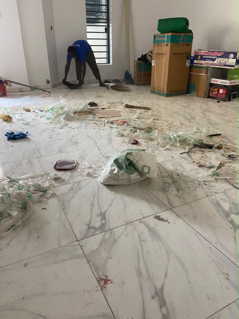 Cleaner sweeping construction waste off a marble floor in a new Lagos building